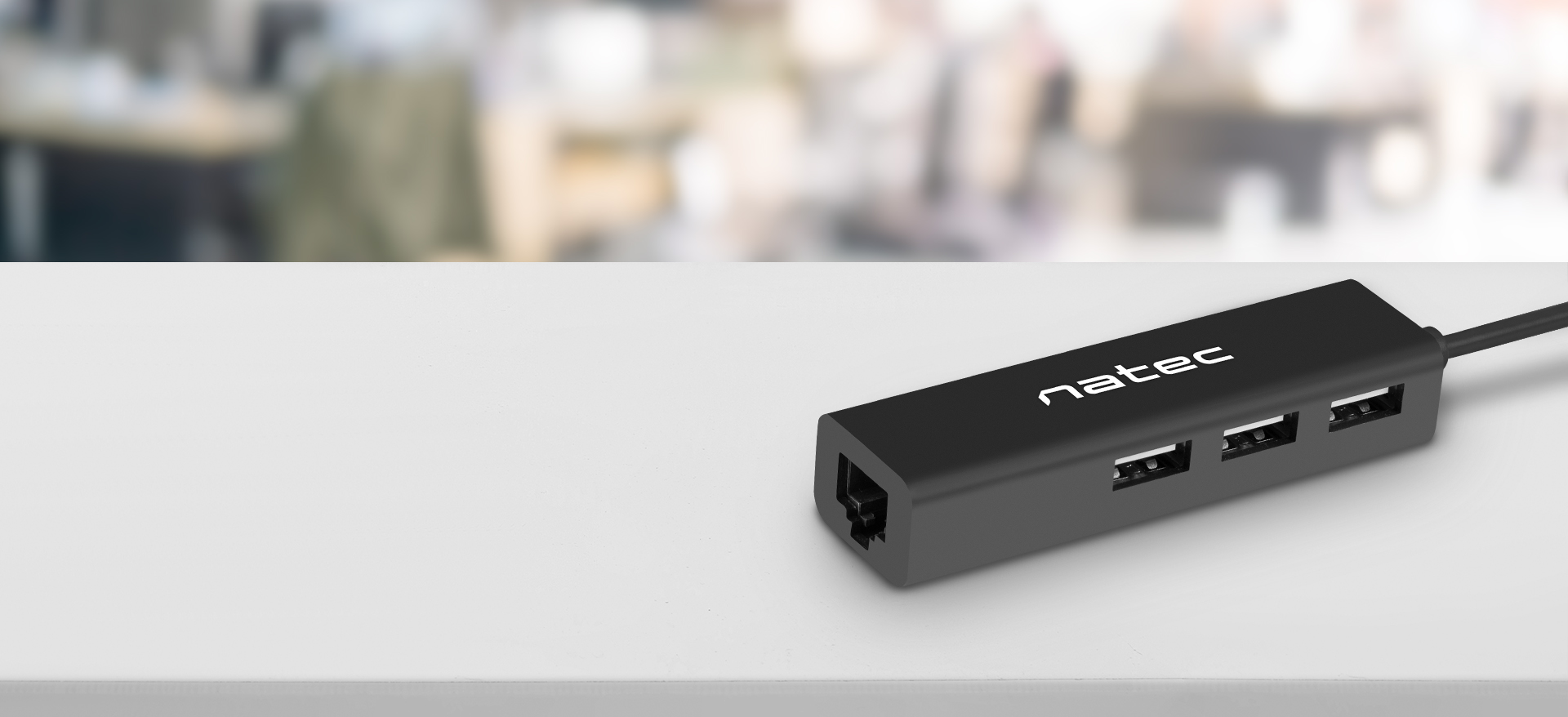 Black device with multiple connection ports and a cable on a light-colored surface.