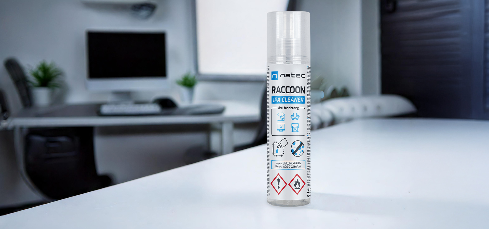 Butelka sprayu czyszczącego na białym stole z nowoczesnym biurem w tle.