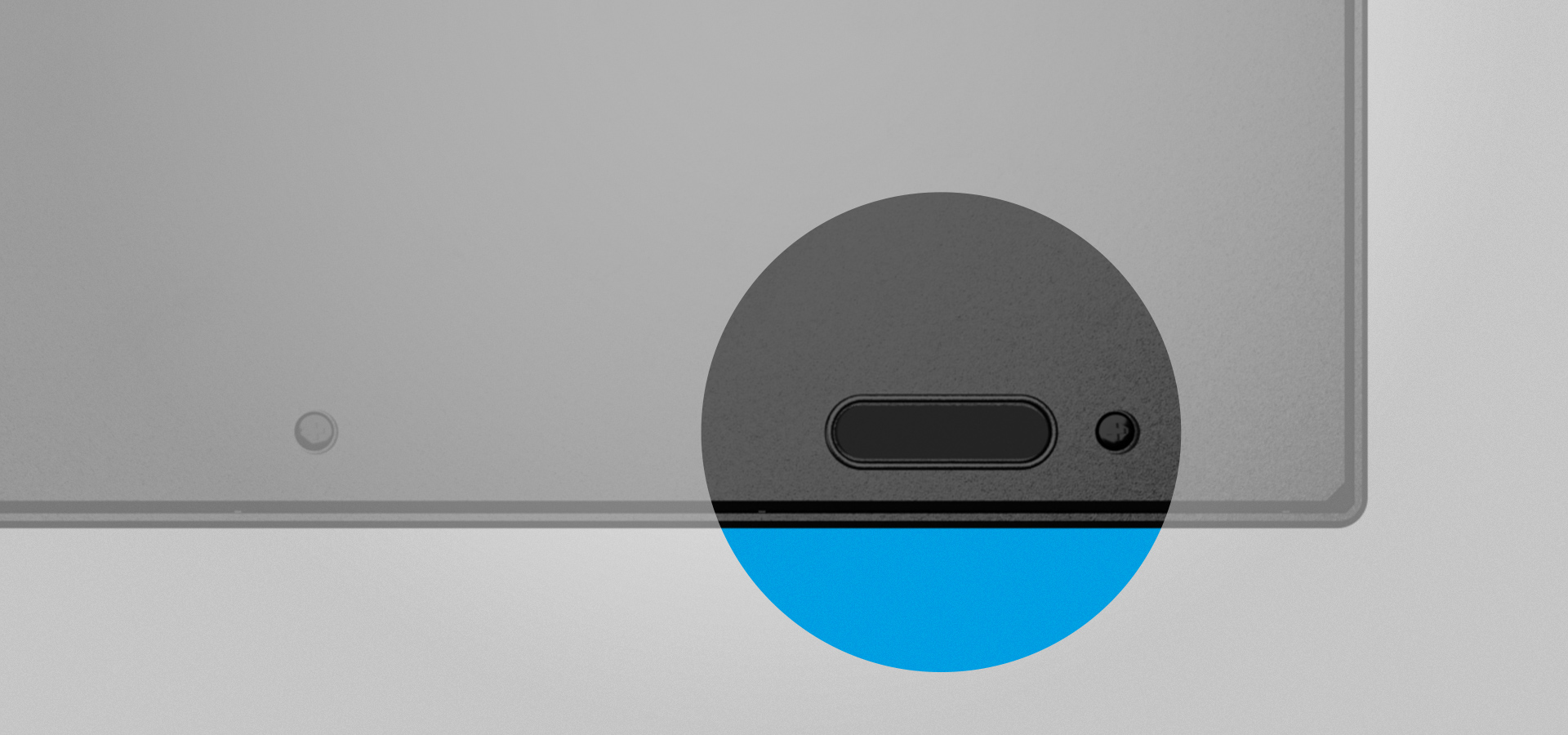 Zbliżenie na róg urządzenia z małym przyciskiem i czarnym obrysem.