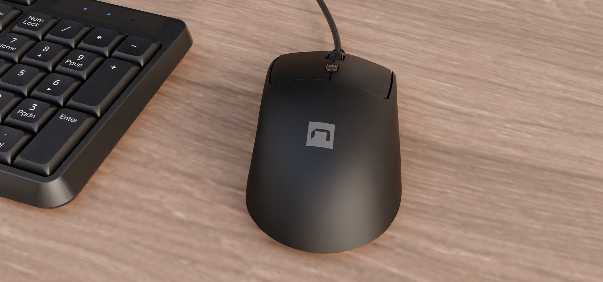 Czarna mysz komputerowa z kablem obok ciemnej klawiatury na drewnianej powierzchni.
