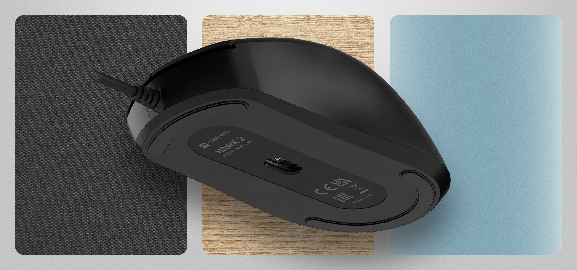 Czarna mysz komputerowa na różnych fakturowanych powierzchniach w szarości, drewnie i błękicie.