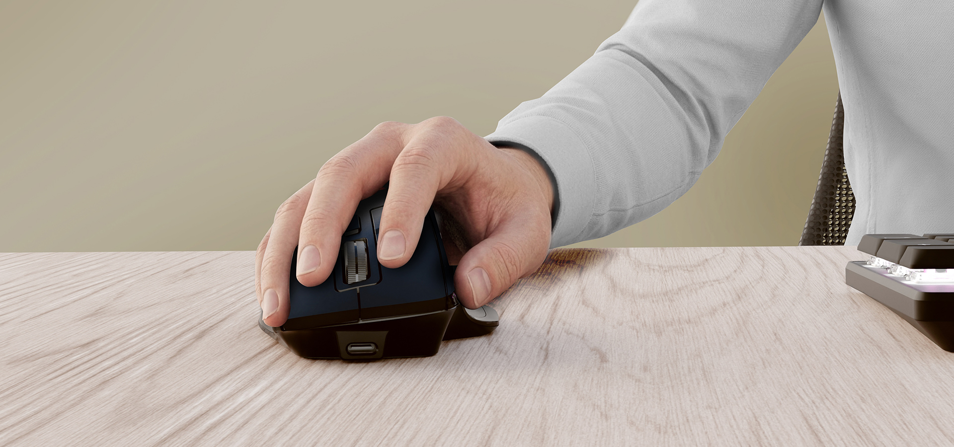 A hand using a computer mouse on a wooden desk with a blurred background.