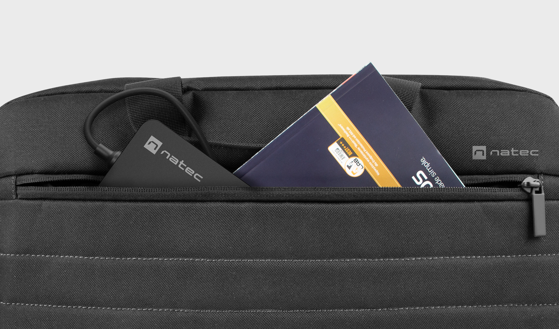 Przenośna ładowarka z kablem i instrukcją umieszczoną w ciemnej kieszeni torby.